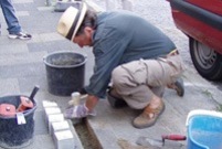 Ein Mann verlegt die glänzenden neuen Stolpersteine in das Pflaster