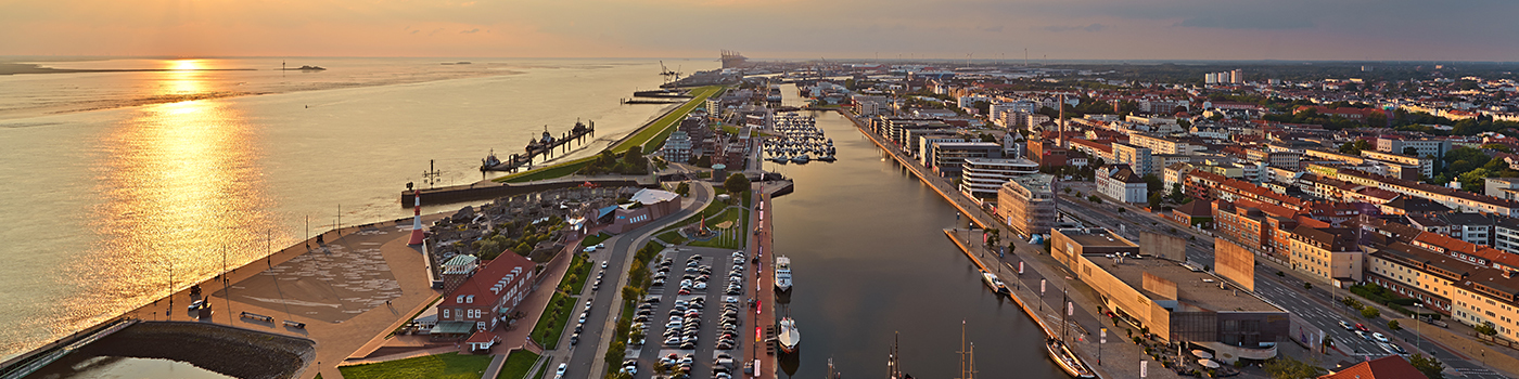 Luftbild von einer Stadt mit Hafenbecken am Wasser gelegen.