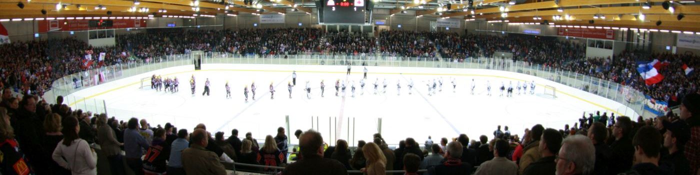 Ice hockey players are standing in an ice arena.