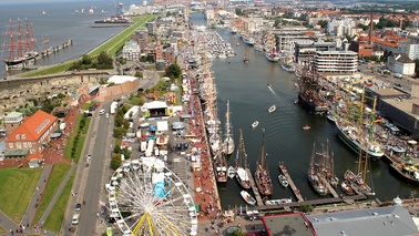 Blick von Aussichtsplattform auf Veranstaltungsgelände, Segelschiffe, Hafen