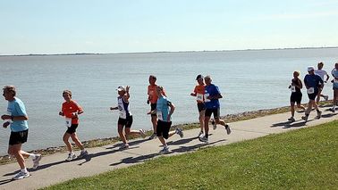 Runners run along the water.