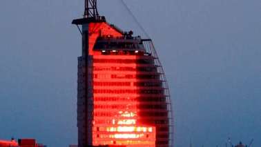 Red illuminated large building, which resembles a sail.