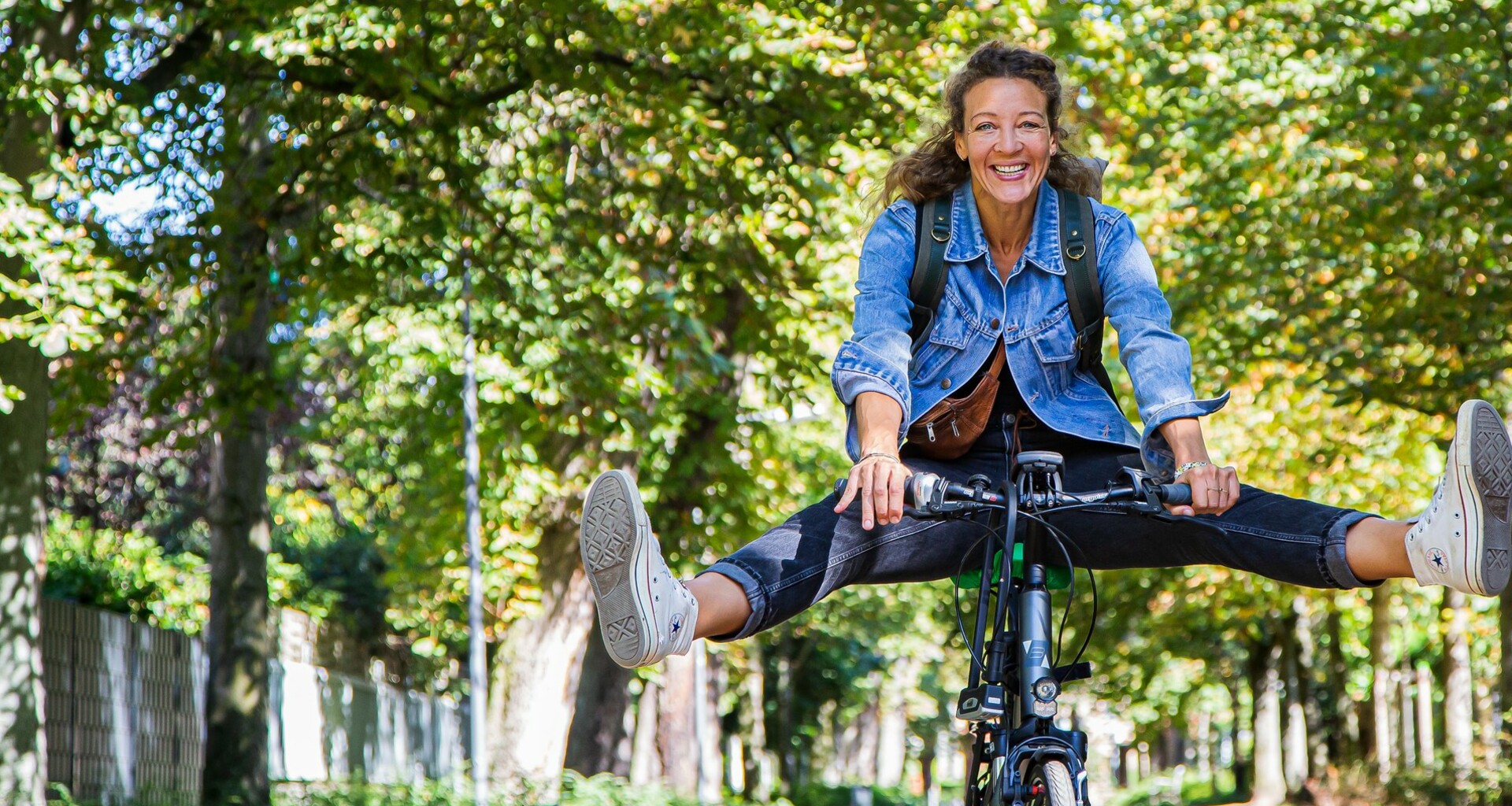 Eine Frau fährt Fahrrad und streckt dabei die Beine in die Luft. 