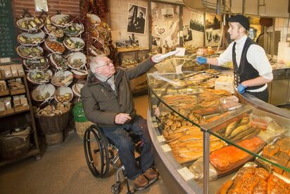 A wheelchair user while shopping in a fish shop.