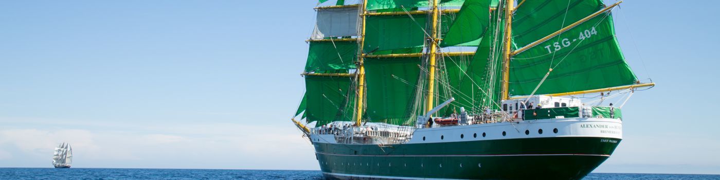 Ein großes Segelschiff mit grünen Segeln.