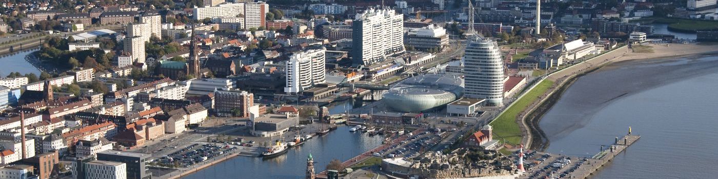 Luftbild von einer Stadt mit Hafenbecken am Wasser gelegen.