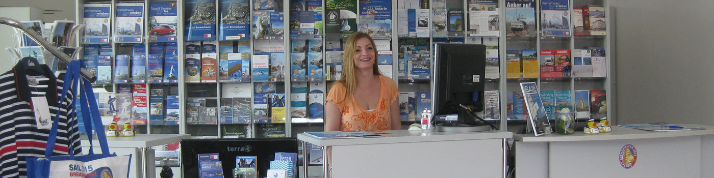 Eine Frau steht in einer Tourist-Information hinter dem Counter.