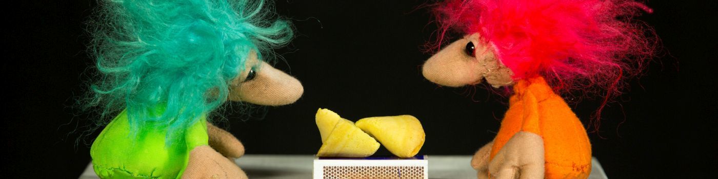 Zwei kleine Figuren mit struppeligen Haaren, einer mit grünen und einer mit pinken. In der Mitte eine geteilte Zitrone.