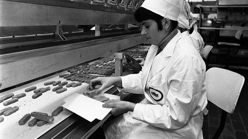 Arbeiterin bei der Verpackung von Fischstäbchen am Fließband um 1970