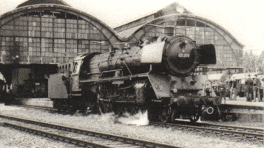Historische Aufnahme eines Bahnhofes mit Lokomotive.