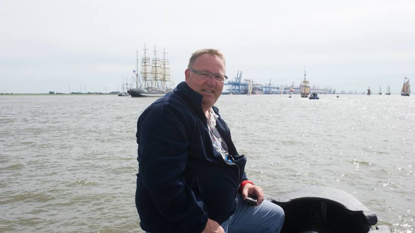 Heino Tietjen sitzt auf einem Boot auf der Weser. Im Hintergrund sind Segelschiffe.