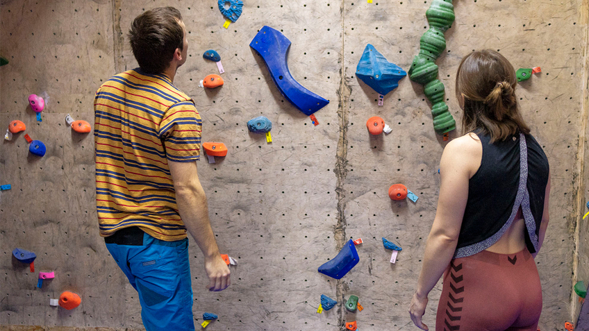 A woman and a man in front of climbing wall