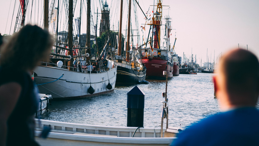 A women left and a men right. They look at the New Harbour with sailing ships in Bremerhaven.