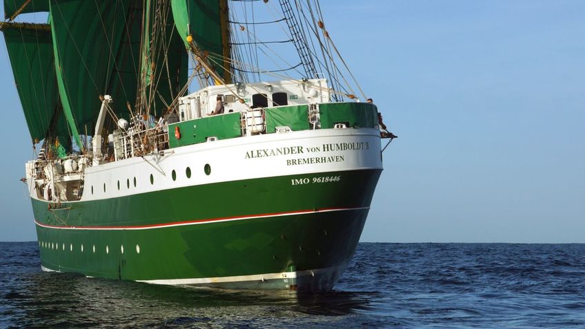 A sailing ship with green sails on a trip.