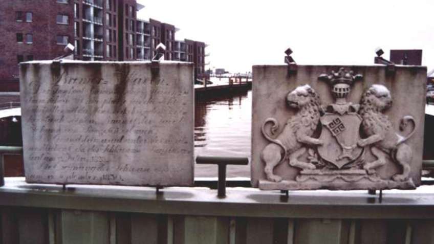 Two plaques of stone, in the background a harbor area.