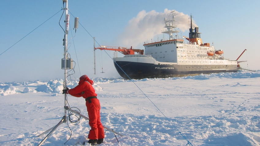 Die "Polarstern" im Eis, davor ein Mann, der Geräte aufstellt.
