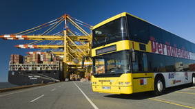 Der Hafenbus auf der Kaje vor Containerbrücken.