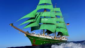 A sailing ship with green sails.