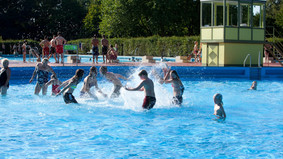 Kinder spielen im Nichtschwimmerbecken.