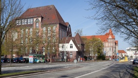 Auf dem Bild sieht man die Wilhelm-Raabe-Schule. Links und rechts im Vordergrund stehen Bäume. 