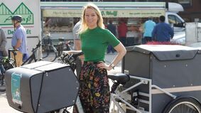 A woman in front of a cargo bike.