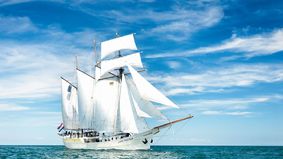 A sailing ship with white sails.