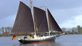 A schooner with brown sails traveling with passengers.