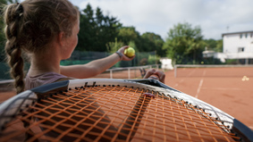 Junge Sportlerin mit einem Tennisschläger auf einem Tennisplatz