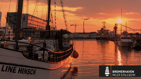 Ein Segelschiff im Schaufenster Fischereihafen Bremerhaven mit einem Sonnenuntergang im Hintergrund.