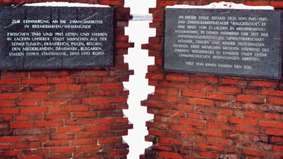 Zwei Gedenktafeln hängen an einer Mauer.