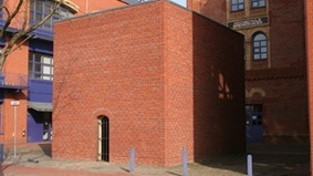Ein quadratisches Gebäude in Backstein.