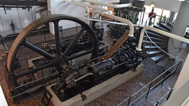 Eine große historische Maschine steht in einem Ausstellungsraum.