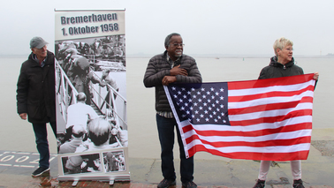 drei Personen mit Flagge auf der Columbuskaje
