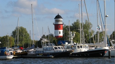 Leuchtturm und liegende Schiffe bei einer Marina.