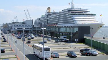 Kreuzfahrt-Terminal mit Parkflächen und einem Kreuzfahrtschiff.