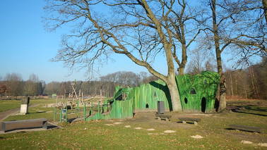 Ein grünes Baumhaus mit einer Rampe zugänglich am Drachenspielplatz