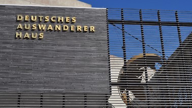 Außenansicht des Deutschen Auswandererhauses: links das Logo in goldener Schrift, rechts eine Weltkugel