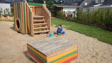 Kleinkindbereich mit buntem Rutschenhaus und Sandspielbereich mit Backkiste