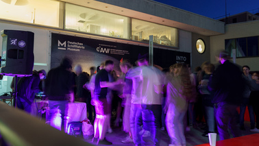 Viele Menschen tanzen zu lila Licht vor dem Deutschen Schifffahrtsmuseum