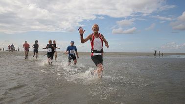 Runners run through the water.