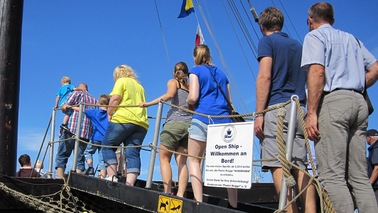 People walk over gangway on a sailing ship