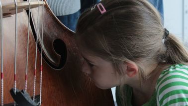 Ein Kind kniet vor einem Instrument.