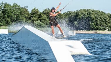 A man is water skiing down a ramp.