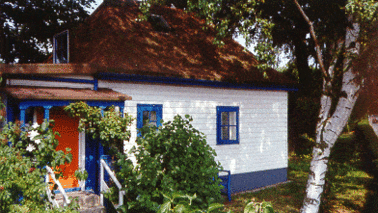 Ein Holzhaus steht in einem kleinen Garten.