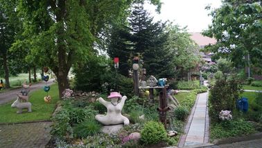 Großer Garten mit Blütenpracht und Skulpturen. 