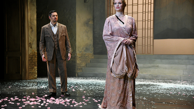 Two dressed up actors on a stage with petals 