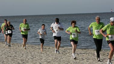 Läufer rennen am Meer entlang.