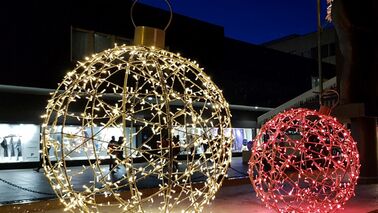 Illuminated balls are standing on a Christmas market.