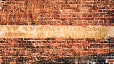 Auf einer Mauer befindet sich eine Inschrift.