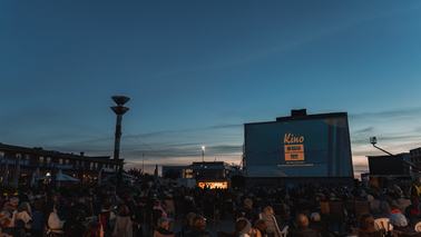 Dämmerung im Schaufenster Fischereihafen. Auf der großen Leinwand läuft der Trailer zum Kino im Hafen 2022.